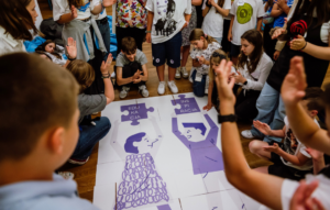 grupa uczniów układająca duże puzzle z napisem edukacja inspiracja